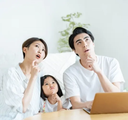 キッチンで家族が3人、小さい女児と夫婦で相談している風景